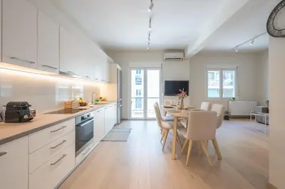a kitchen with white cabinets and a table with chairs at Stylish 2BDR Apt by the Acropolis in Athens
