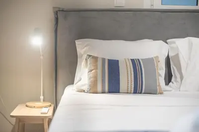 a bed with white pillows and a lamp on a table at Stylish 2BDR Apt by the Acropolis in Athens