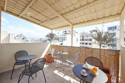 a patio with tables and chairs on a balcony at Wake up with Acropolis view! in Athens