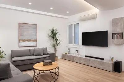 a living room with a couch and a tv on a wall at Acropolis Holmes Residence in Athens