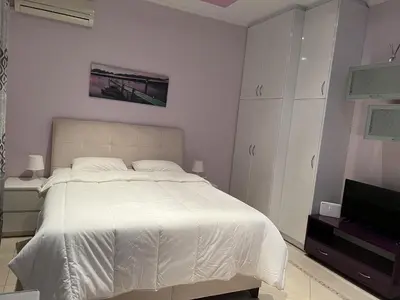 a white bedroom with a bed and a tv at Piraeus Cozy Stylish, Fully Reno Apt, near metro in Piraeus
