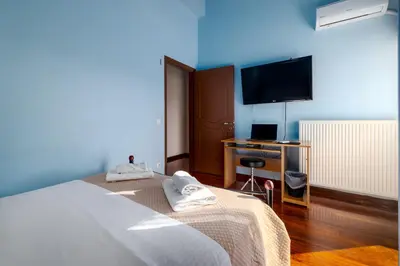 a blue room with a bed and a television at Spacious Villa with pool 500m from the beach in Vari