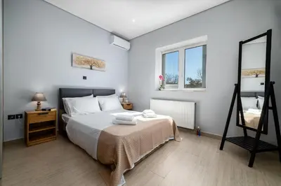 a white bedroom with a bed and a mirror at Spacious Villa with pool 500m from the beach in Vari