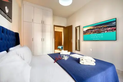 a bedroom with a bed with a blue blanket and a tv at Blue Horizon - City Center Close to Metro in Athens
