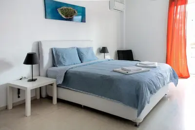 a bedroom with a bed with blue sheets and a table at Meandros apartment city center in Athens