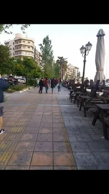 a group of benches and people walking down a street at Piraeus historical center in Piraeus