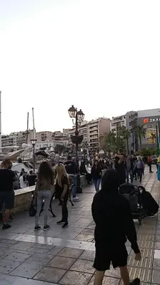 a group of people walking on a city sidewalk at Piraeus historical center in Piraeus