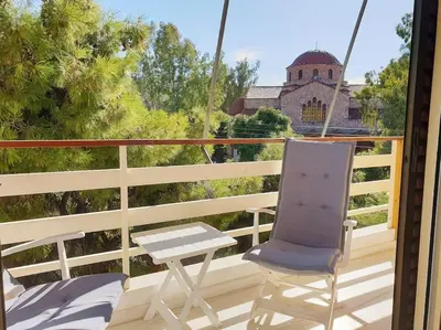 a chair on a balcony with a view of a church at Rooftop Studio Apt - 5 Min Walk to Holargos Metro in Athens