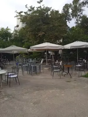 a bunch of tables and chairs with umbrellas at Santorini Style at Nathional Archeological museum of Athens,Greece in Athens