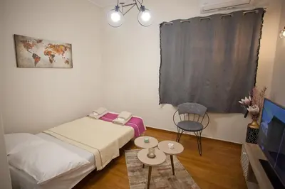 a small room with two beds and a tv at Lovely Nest Piraeus in Piraeus