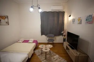 a small room with two beds and a tv at Lovely Nest Piraeus in Piraeus