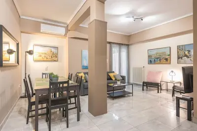 a dining room and living room with a table and chairs at Pegasus Apartment in Piraeus