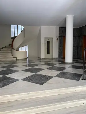 an empty room with a checkered floor and stairs at Palace Apartment in Athens