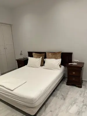 a bed with white sheets and pillows and two tables at Palace Apartment in Athens