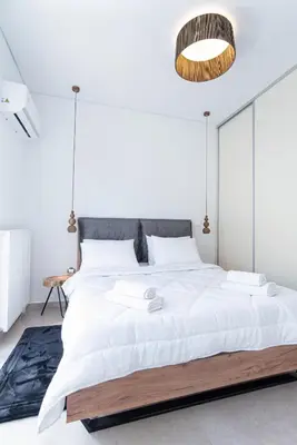 a bedroom with a large white bed with a wooden frame at 2bdroom Plaka Apartment in Athens