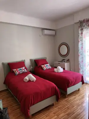 two beds in a bedroom with red sheets and a mirror at Studio Next to Acropolis in Athens