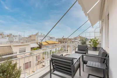 a balcony with chairs and a table and a view of a city at The HostMaster Cosmopolitan Downtown Scent in Athens