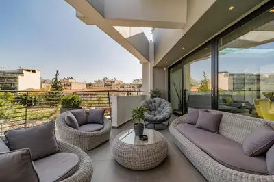 a balcony with wicker couches and a table at The HostMaster Skyline Pool Oasis Penthouse in Athens