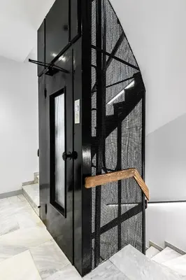 a black door with a wooden rail next to it at Mosaikon Glostel in Athens