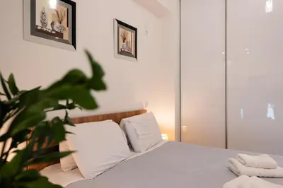 a bedroom with a bed with white sheets and a plant at Modern studio apartment A in Athens