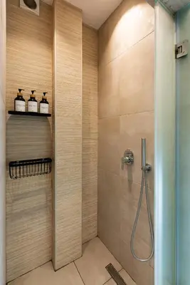 a bathroom with a shower with three bottles on a shelf at Modern studio apartment A in Athens