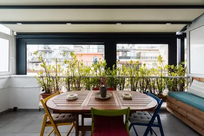 a wooden table and chairs on a balcony with a window at Modern studio apartment A in Athens