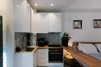 a kitchen with white cabinets and a bed in a room at Modern studio apartment A in Athens