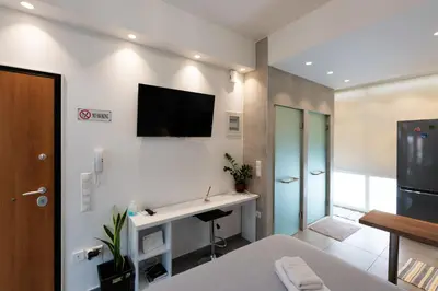 a bedroom with a desk and a television on the wall at Modern studio apartment A in Athens