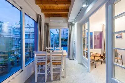 a dining room with a table and chairs and windows at Modita Boutique Apartments in Athens