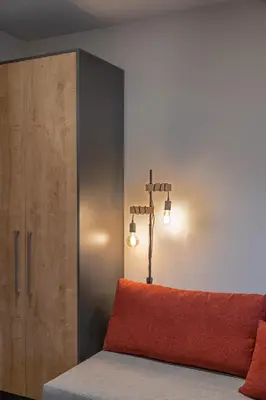 a bed with an orange pillow next to a cabinet at Exarchia House Project in Athens