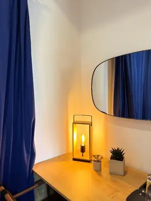 a light on a wooden table with a blue curtain at Exarchia House Project in Athens