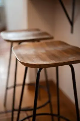 two wooden stools sitting next to a wall at JUST KOLONAKI in Athens