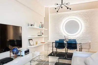 a living room with a glass table and blue chairs at Lux Beach Apartment in Vari