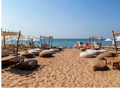 a sandy beach with benches and umbrellas and the ocean at Lux Beach Apartment in Vari
