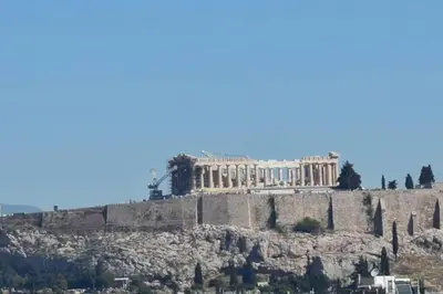 a building on top of a hill with trees at Overlooking the Acropolis in Athens