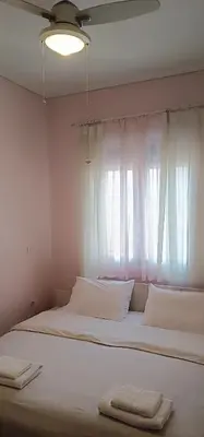 a bedroom with a bed with white sheets and a window at Overlooking the Acropolis in Athens
