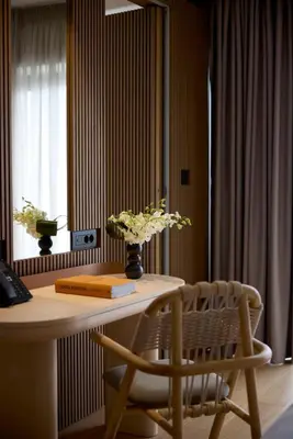 a table and a chair with a vase of flowers on it at Dusit Suites Hotel Athens in Athens
