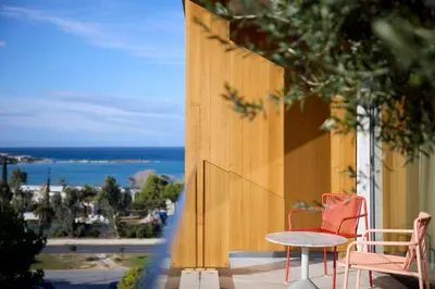 two chairs and a table on a balcony with a view of the ocean at Dusit Suites Hotel Athens in Athens