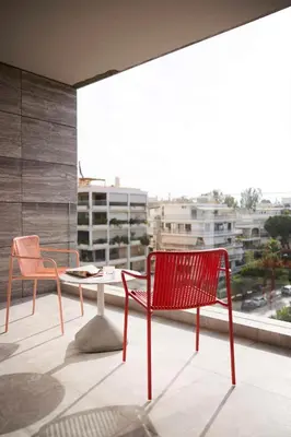 two red chairs and a table on a balcony at Dusit Suites Hotel Athens in Athens
