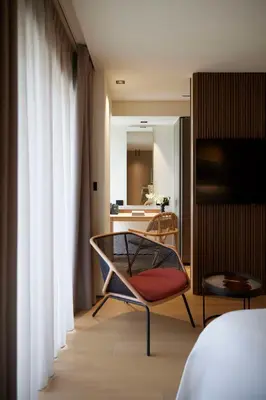 a room with a bed and a chair and a mirror at Dusit Suites Hotel Athens in Athens
