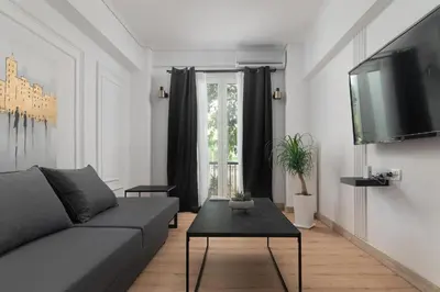 a living room with a couch and a table and a tv at Athenian Postmodern Gem in Athens