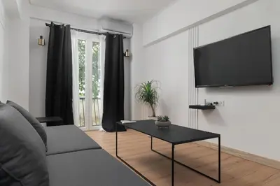 a living room with a couch and a tv on a wall at Athenian Postmodern Gem in Athens