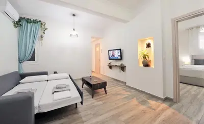 a white living room with a couch and a bed at Bella Ciao Guest House in Athens