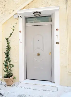 a white front door of a house with a potted plant at Bella Ciao Guest House in Athens