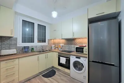 a kitchen with white cabinets and a washer and dryer at Bella Ciao Guest House in Athens