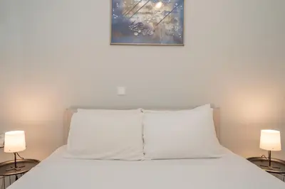 a bed with a white pillow and two lamps at Renovated Lovely Apt next to Marina Flisvos in Athens