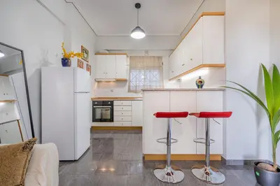 a kitchen with white cabinets and red bar stools at Renovated Lovely Apt next to Marina Flisvos in Athens