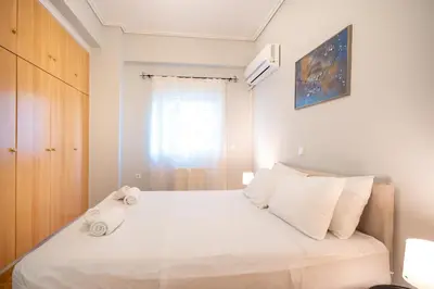 a bedroom with a bed with white sheets and a window at Renovated Lovely Apt next to Marina Flisvos in Athens