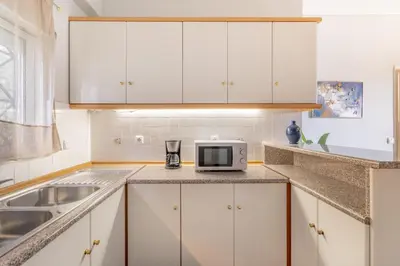 a kitchen with white cabinets and a microwave at Renovated Lovely Apt next to Marina Flisvos in Athens
