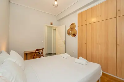 a bedroom with a white bed and a wooden cabinet at Renovated Lovely Apt next to Marina Flisvos in Athens